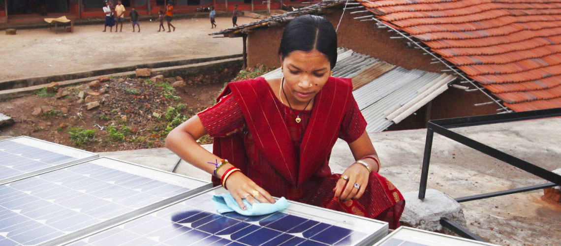 Image of woman cleaning a solar panel that powers her farm.