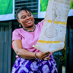 a smiling woman holds up a large piece of paper with a diagram and text