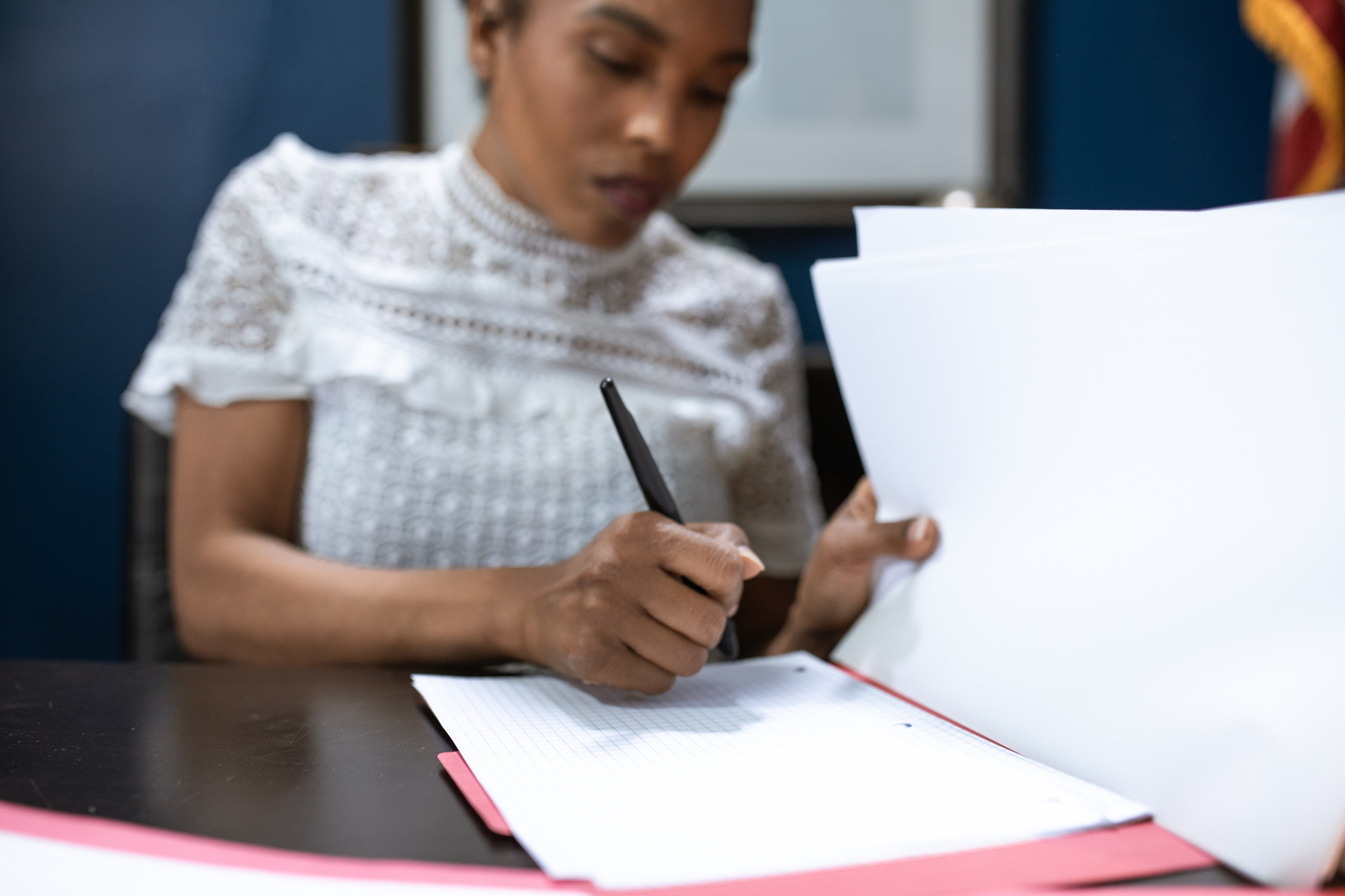 A woman fills out a ballot form with a pen