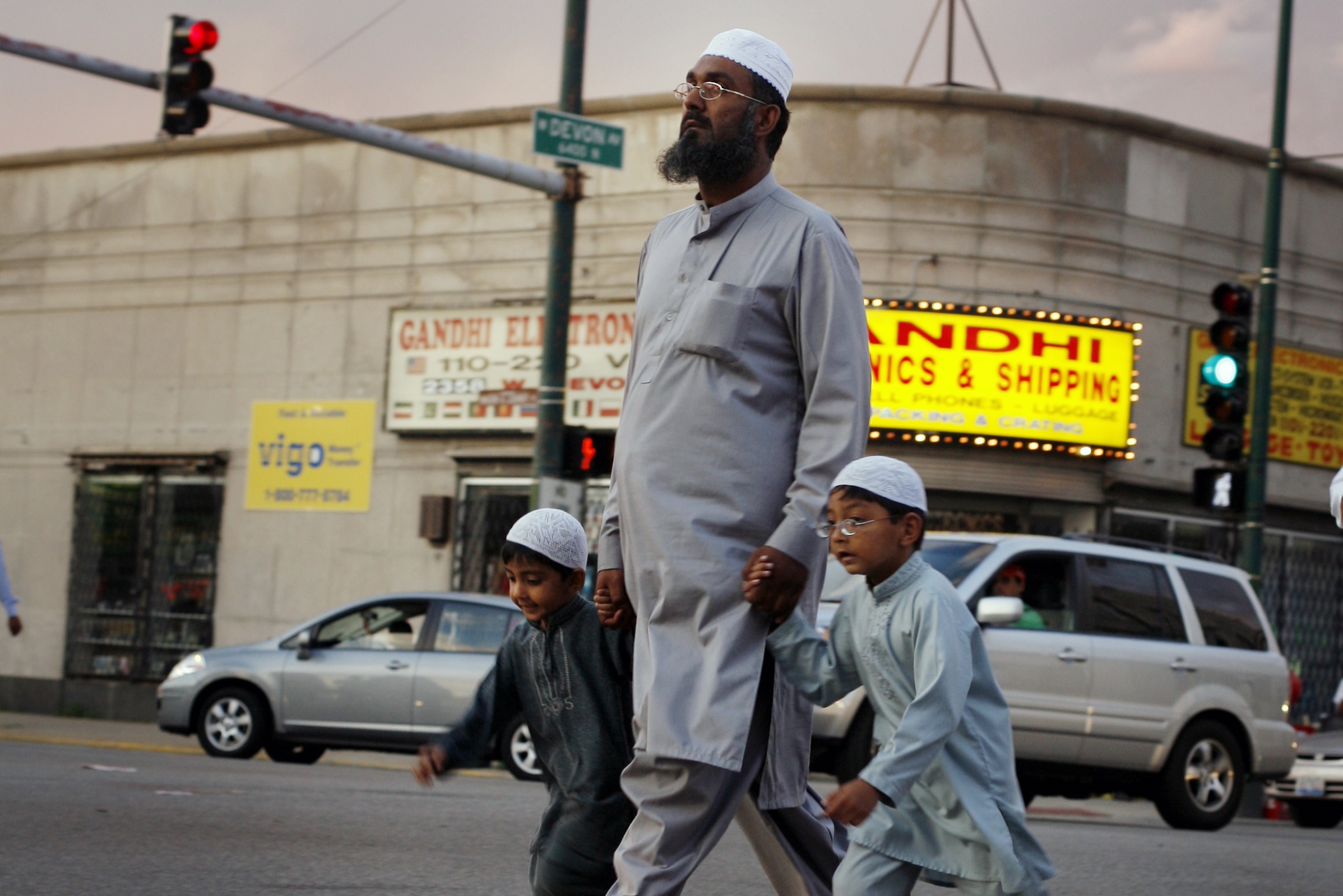 A man holds the hands of two boys while crossing the street