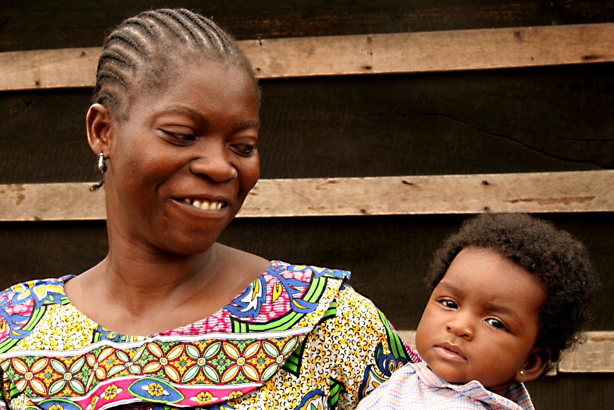 A mother smiles while holding a baby