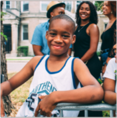 smiling young boy in tank top with other happy people in background