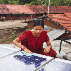 Indian woman cleaning surface of a solar panel