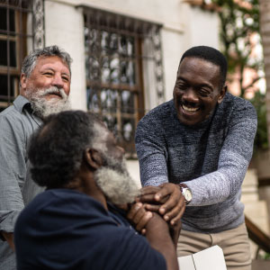 Three men interact warmly with smiles