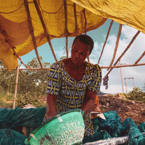 a woman with a green bowl under a bamboo structure with bright yellow canopy