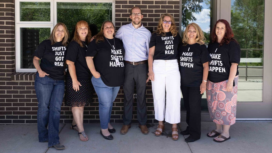 Seven people standing in front of a brick wall for a group shot