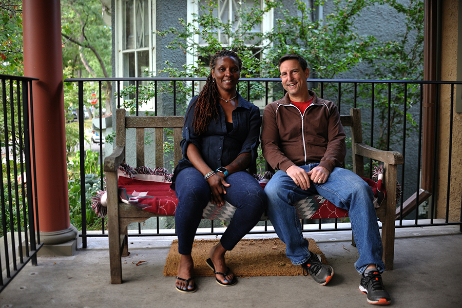 Smiling Black woman and White man sitting together on front porch bench