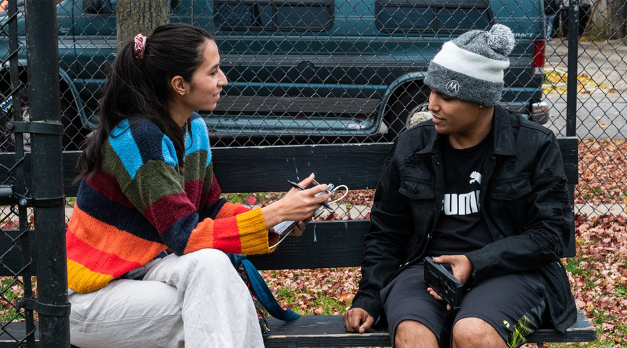 A reporter speaks to a Chicago resident on a park bench