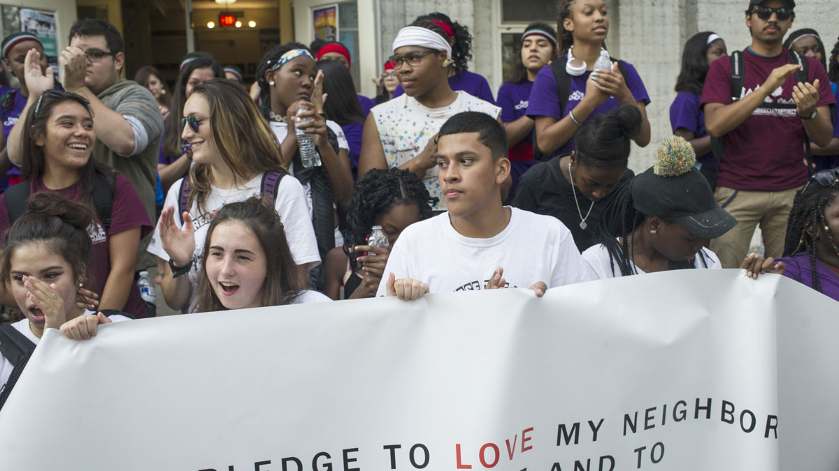 A diverse group of people holding a large banner at a rally.
