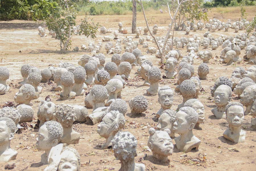 many sculptured heads placed on a desert ground