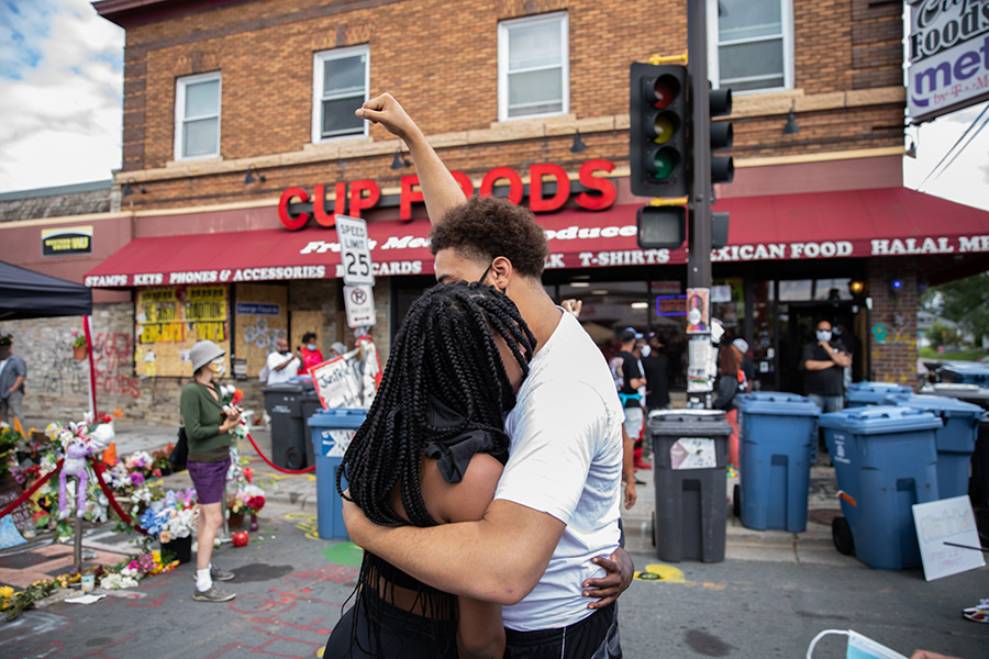 Black man and woman embracing in front of Cup Food convenience store