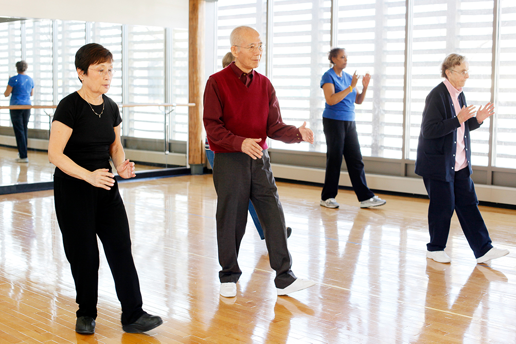 Group of diverse elderly people practicing Thai Chi in a dance studio