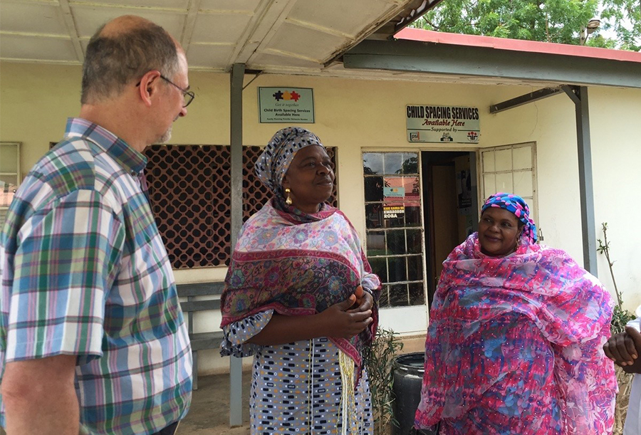 A man and two women are standing and having a conversation. 