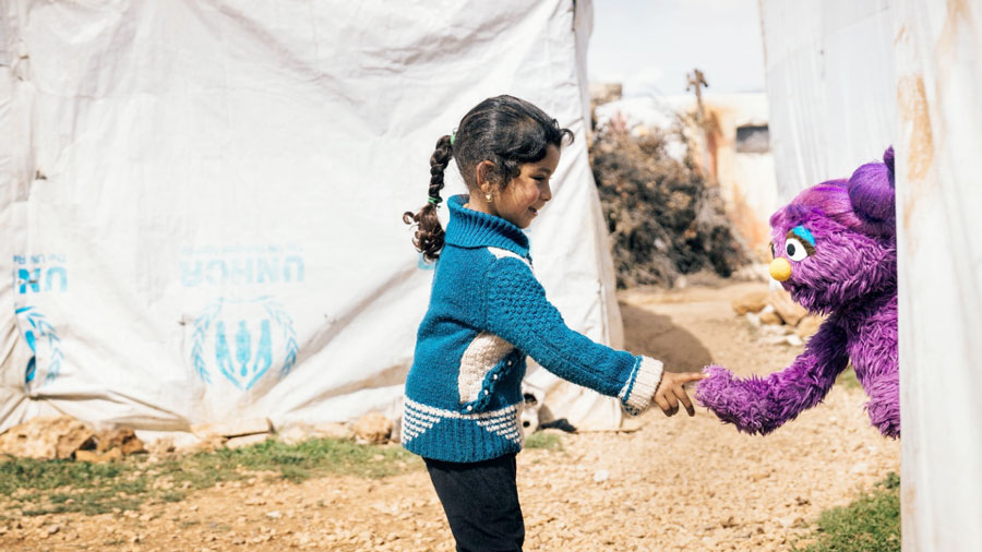 A child shaking hands with a purple puppet