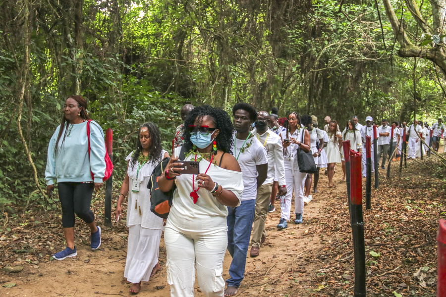 large group of people wearing white walking a jungle path