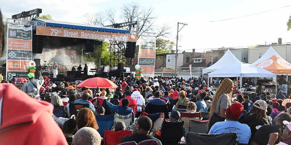 A vibrant crowd of people celebrate in the street during a community fair.