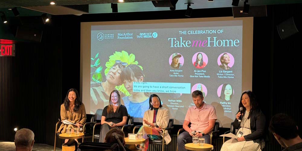 A panel of actors sits in front of a video screen, displaying the title and cast of a recent film project called Take Me Home. A moderator sits nearby with a microphone, ready to lead a discussion about the film. 