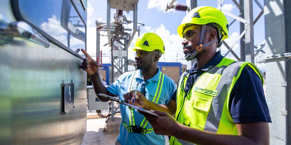 Two men in safety gear inspecting industrial equipment outdoors.
