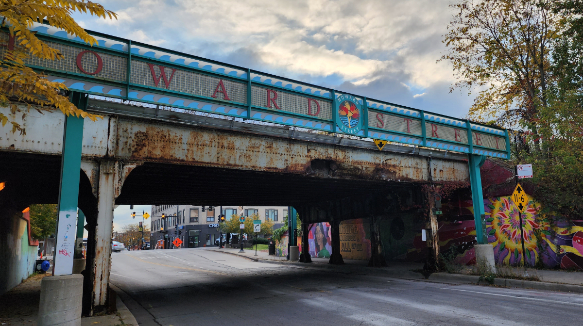A rusty metal train bridge with a sign reading
