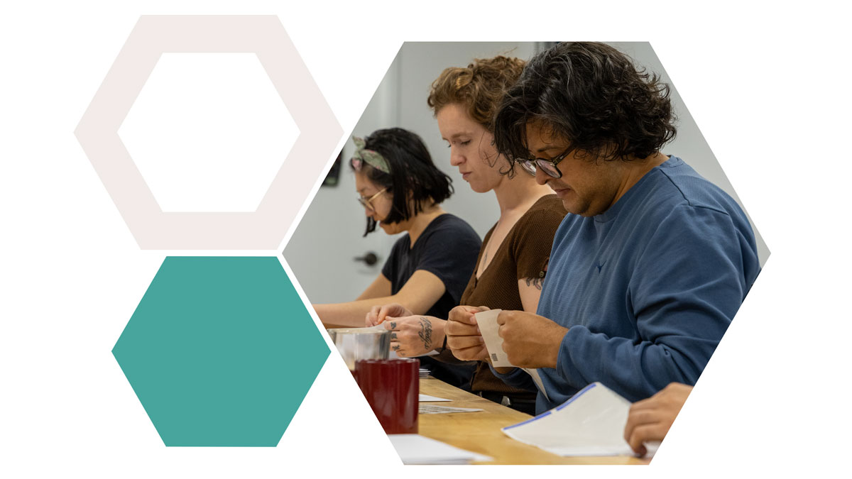 A group of three people engaged in letter campaign activities at a table, alongside geometric hexagon designs.