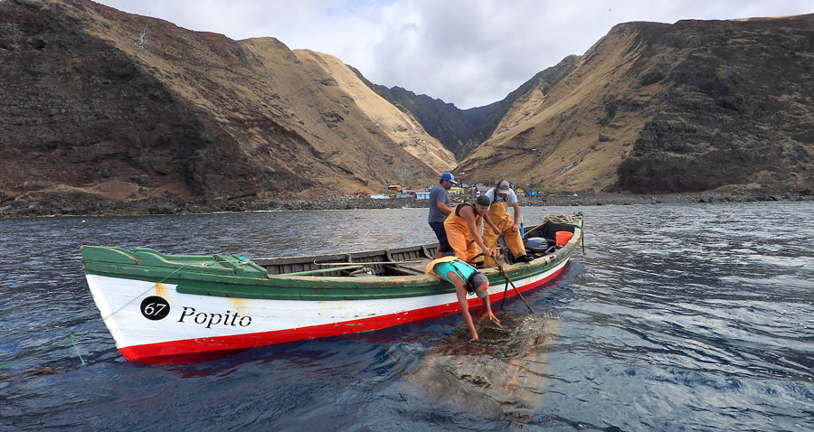 Fishermen in small boat off of mountain coastline