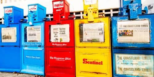 Colorful newspaper vending machines display local newspapers, including The Virginian-Pilot and The Coastland Times.