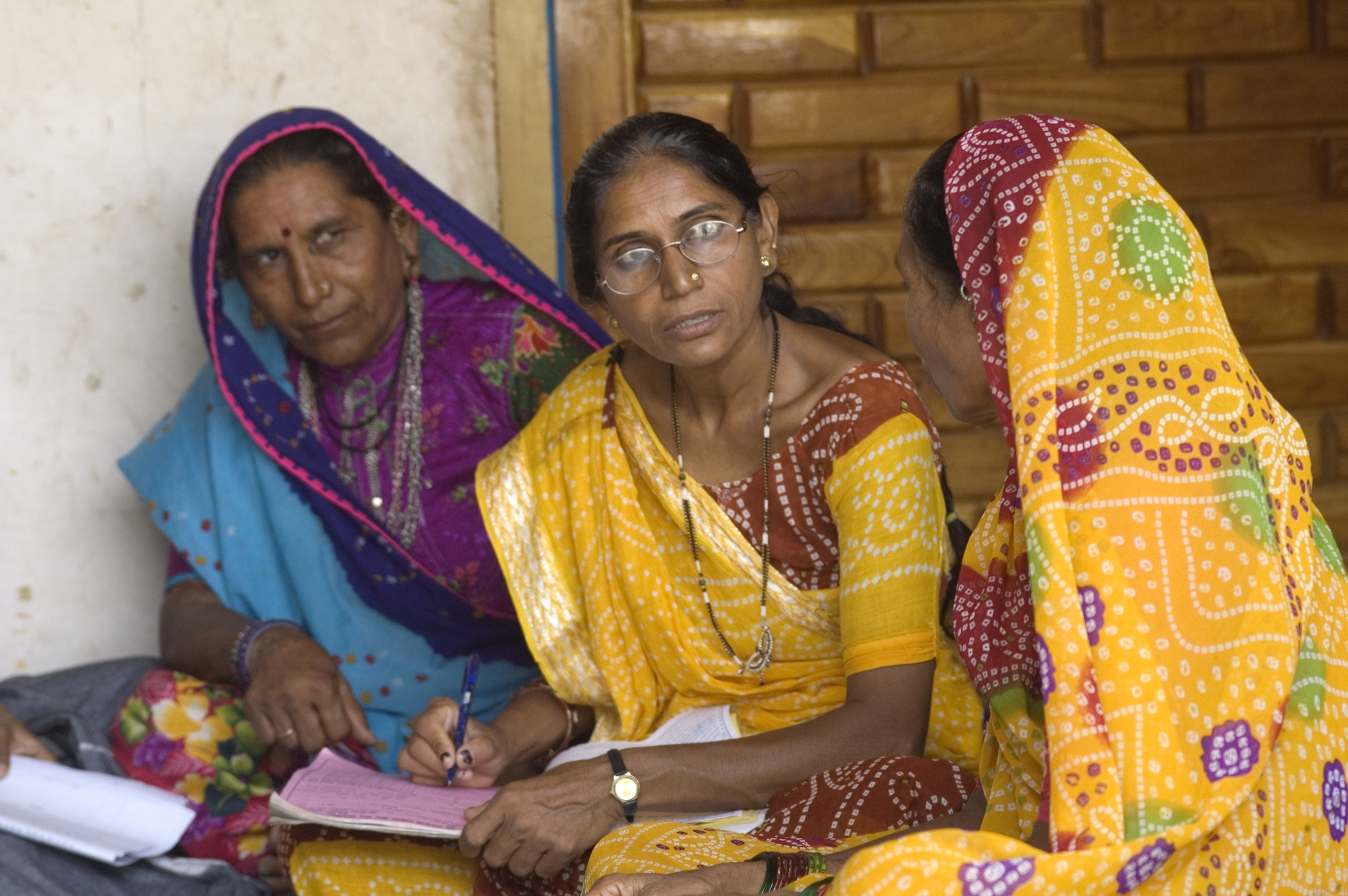 Three seated Indian women in saris talking to one another