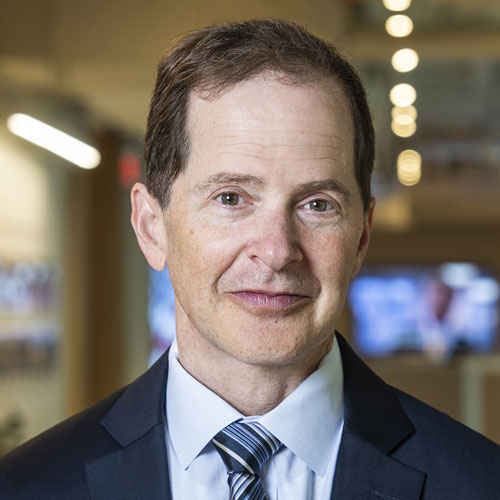 A shoulders-up portrait of Max Steir, President and CEO, Partnership for Public Service. He wears a blue blazer and tie and looks straight ahead.