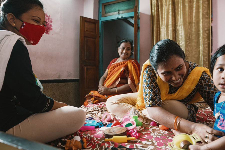 A group of women sitting and smiling, while one woman smiles at a child.