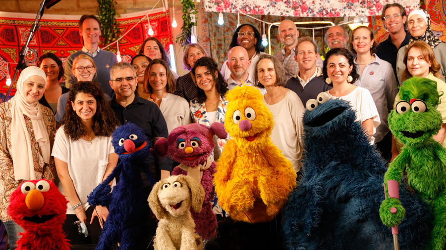 A group of people pose for an image with the Sesame Street puppets
