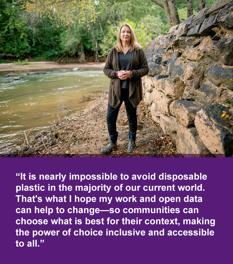 A woman in dark clothes stands next to a stone embankment near flowing water