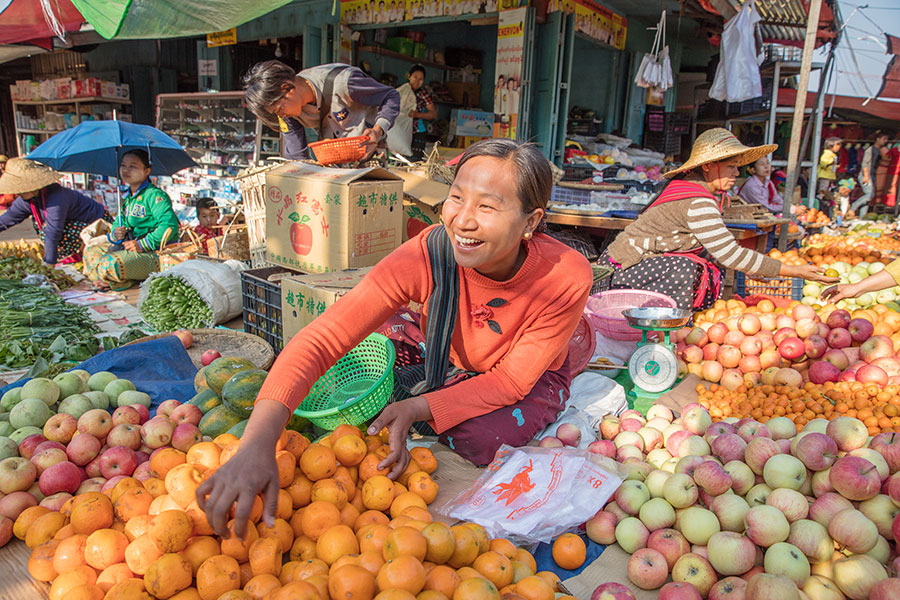 AsianWomanAtFruitMarketReachingForOranges