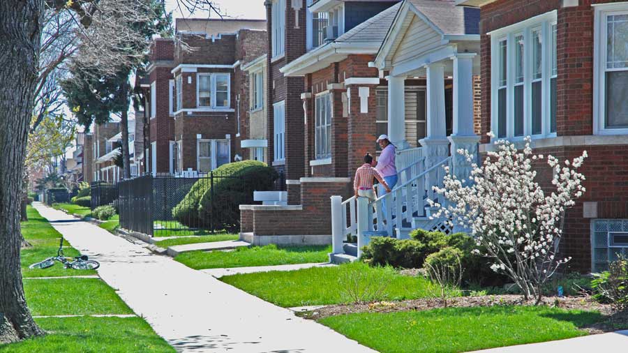 two people talking on the stairs of a house in a neighborhood.