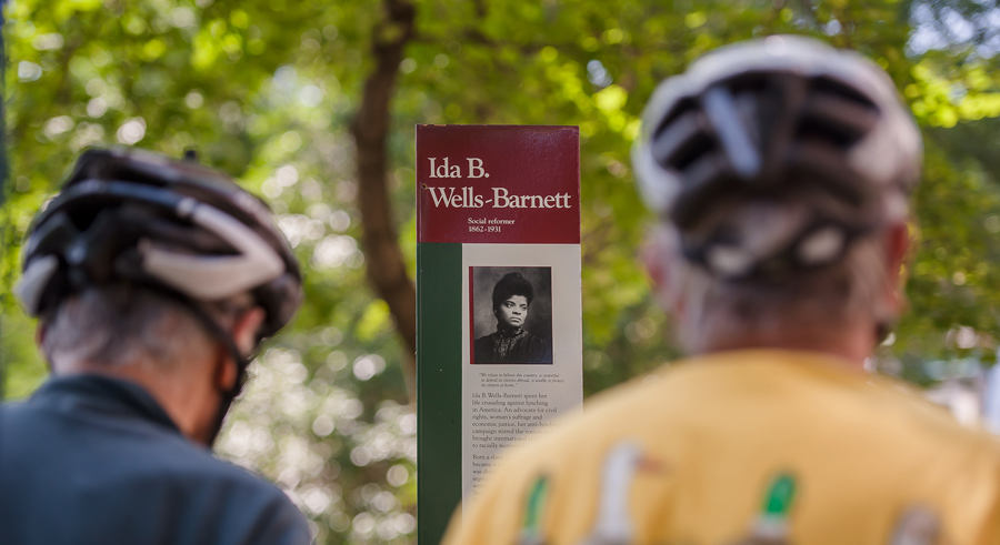Two_Cyclists_Looking_At_Sign_With_Bio_Of_Ida_B._Wells-Barnett
