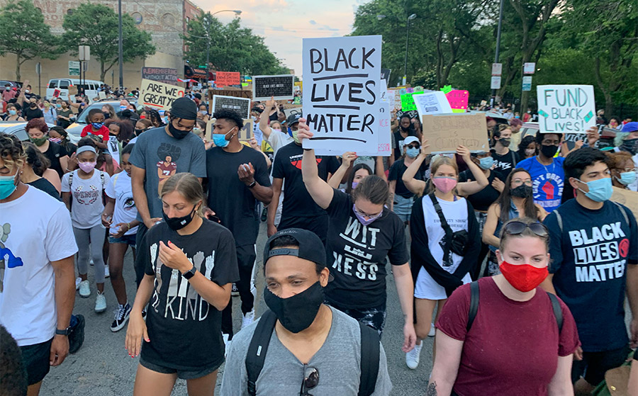 LargeGroupOfPeopleWalkingDownStreetHoldingBlackLivesMatterSigns