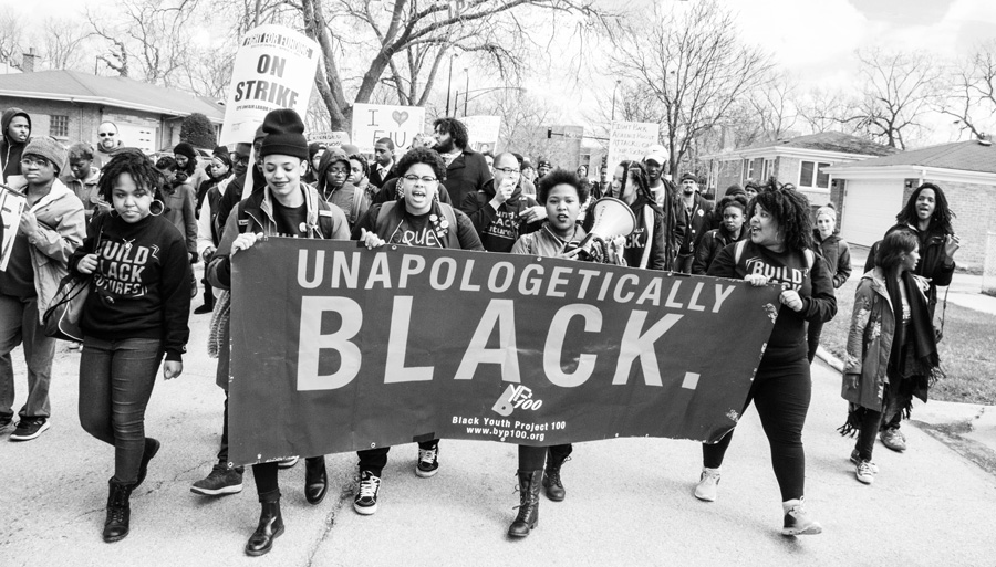 GroupOfBlackPeopleMarchingInNeighborhoodWithUnapologeticallyBlackBanner