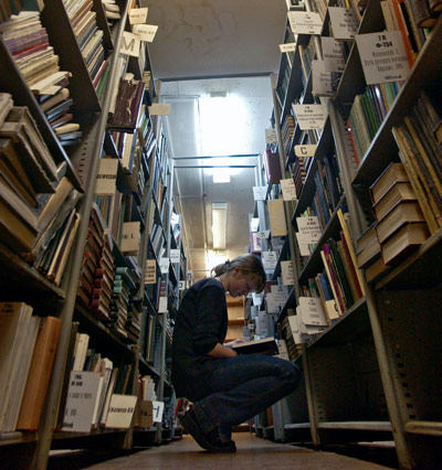 femalestudentbetweentwolibrarybookshelves