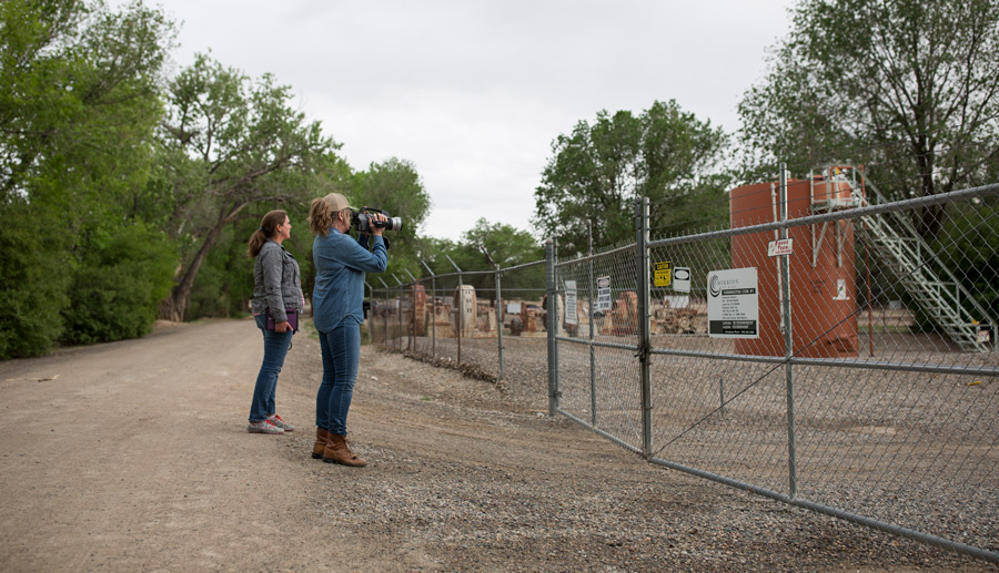 Two_Women_Using_Infrared_Camera_Outside_Fenced_Area_With_Oil_Well