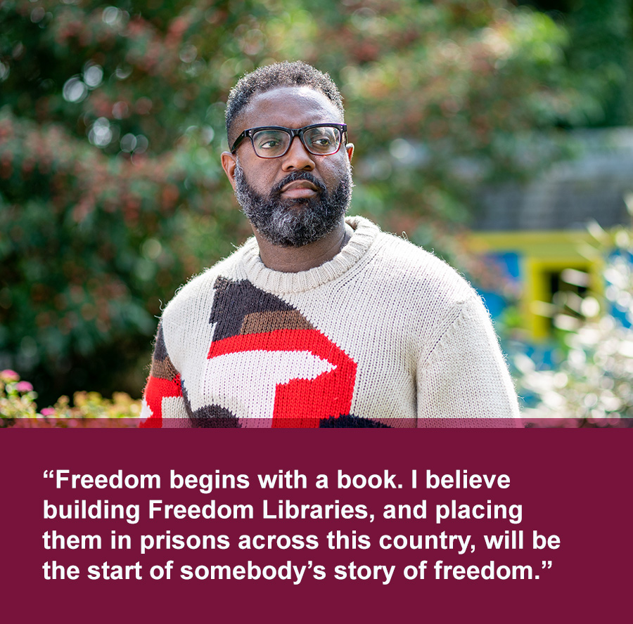 Middle aged Black man with beard and black frame glasses wearing a sweater with green trees in background. Quote text below photo reads: Freedom begins with a book. I believe building Freedom Libraries, and placing them in prisons across this country, will be the start of somebody’s story of freedom.
