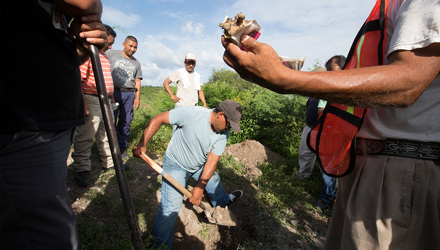 A volunteer citizen police member holds up a bone fragment found during a dig for human remains on the outskirts of Iguala, Mexico.