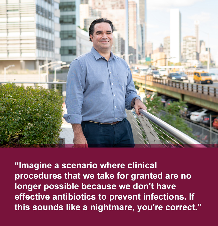 Smiling Latino man wearing a light blue button down shirt stands in urban landscape with buildings behind and highway in background. Quote text below photo reads: Imagine a scenario where clinical procedures that we take for granted are no longer possible because we don't have effective antibiotics to prevent infections. If this sounds like a nightmare, you're correct.
